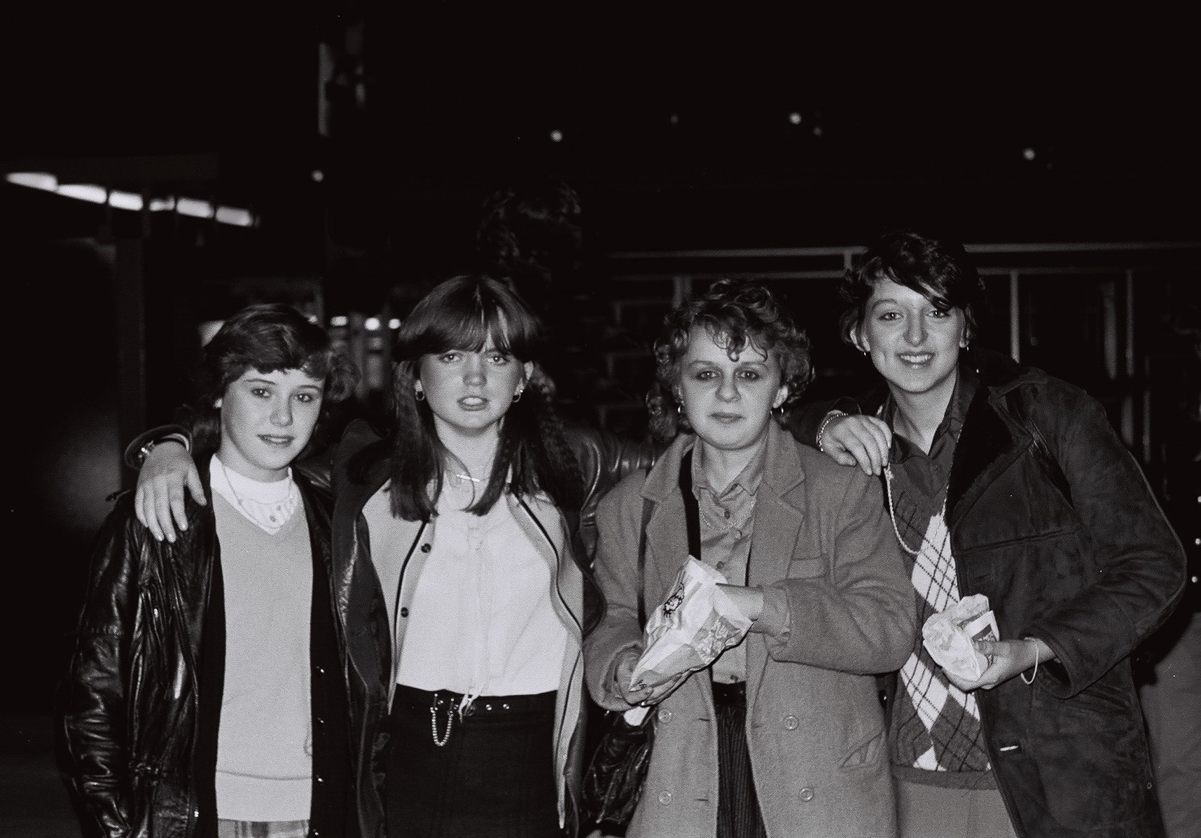 Group of teenage girls outside a west London club, UK 1983. Teenage girls outside a club eating fast food, West London, UK, 1983 by Mark Charnock.