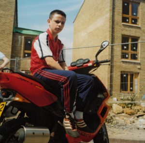 Boy sitting on a moped in a newly built housing complex