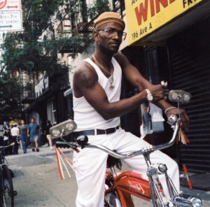 Man on his schwinn bike wearing white jeans and a vest USA