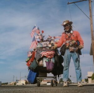 Man with all his belongings in a shopping trolley covered in american flags, USA