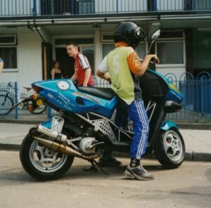 Boy on a motorbike outside a housing estate, UK, 1990s